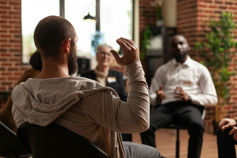 a-man-holding-up-his-hand-in-group-therapy